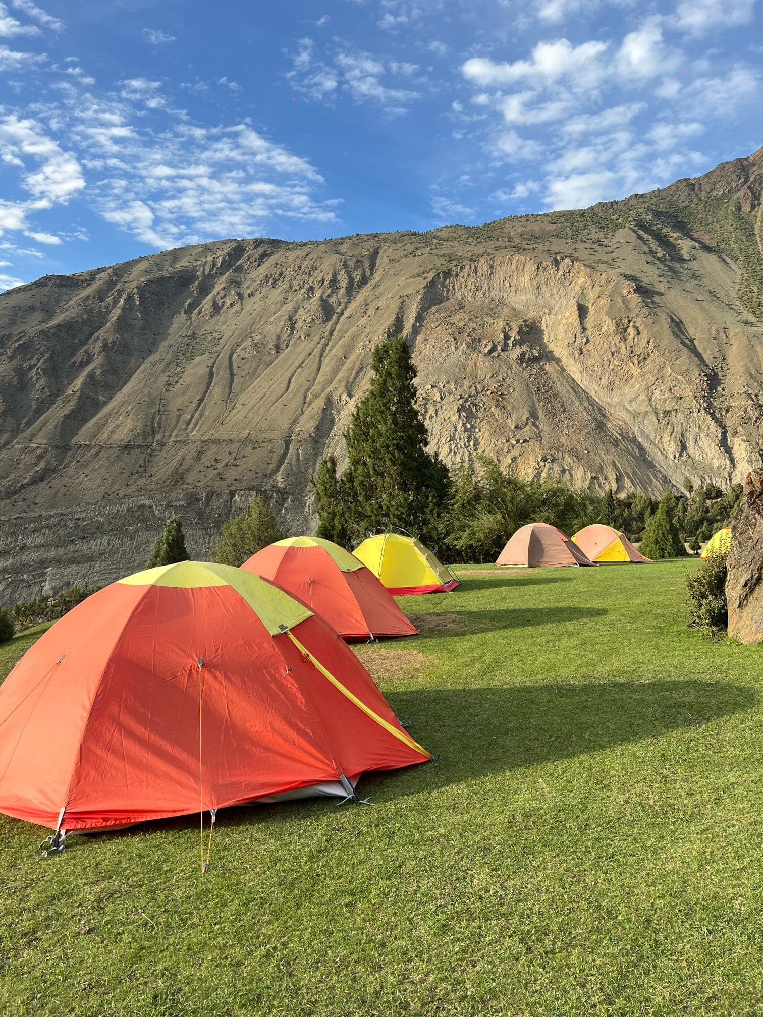 Travelers at a mountain camp below snowy peaks